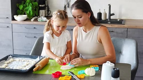 Child and Adult Cutting Cookie Dough in Kitchen