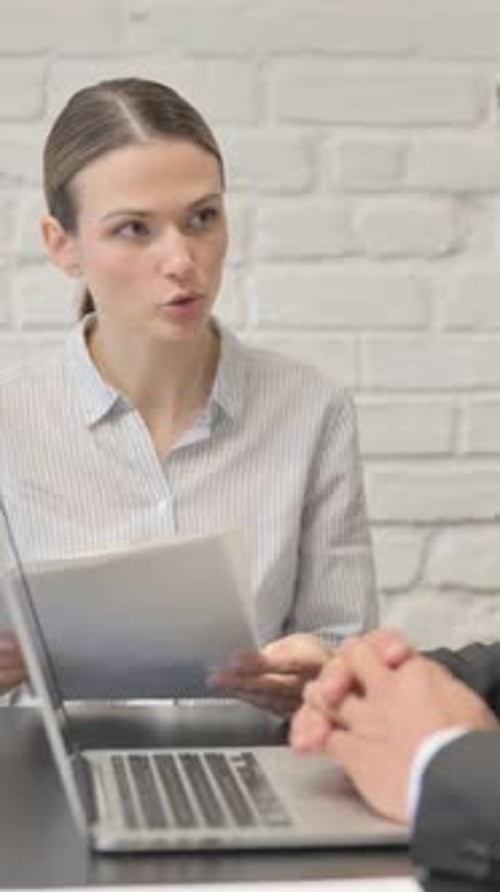 Businesswoman Reviewing Documents with Coworker at Desk
