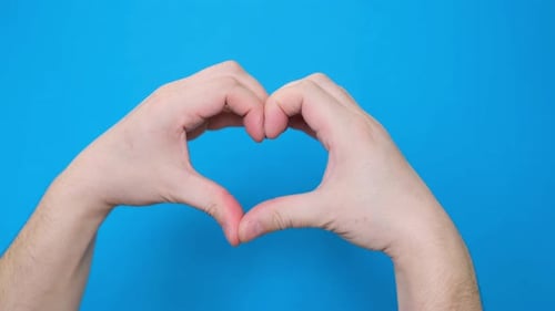 A View of a Male Hand Making a Heartshaped Gesture Isolated on a Blue Screen Chromakey Background