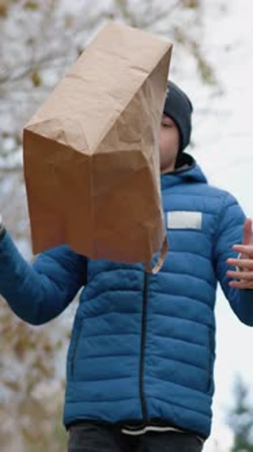 Boy Walking and Pouring Dry Leaves From Bag in Autumn Forest