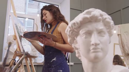 Focused Female Artist Painting in a Studio