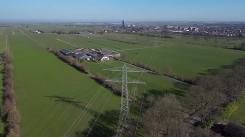 Ein 4K-Luftvideo, das am Abend gedreht wurde, zeigt Stromleitungen, die sich über weitläufiges Ackerland erstrecken. Das lange
