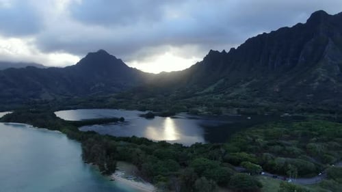 Foto aérea da Baía de Kaneohe e do lago de peixes Molii enquanto o sol se põe atrás de uma dramático montanha