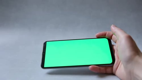 Woman Hand Holding Cell Phone Touch Green Screen Using App on Concrete Stone Grey Background
