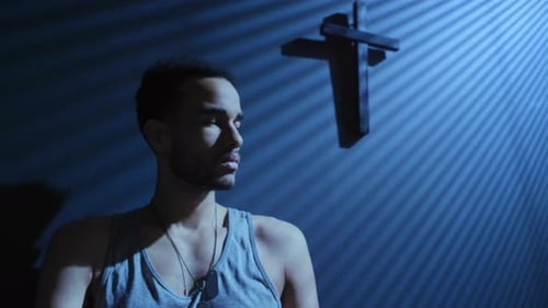 Man with Cross in Dark Room