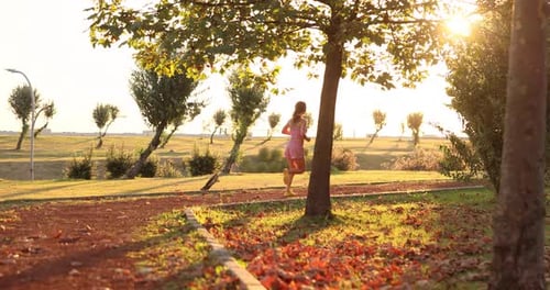 Woman Running on Path in Park at Sunset