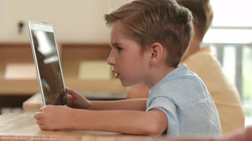 Side view of caucasian boy working on laptop while coding prompt. Pedagogy.