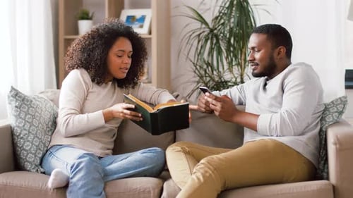 Couple Relaxing at Home with Book and Phone
