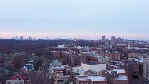 Drone rise over central Brooklyn, New York, just before sunset, revealing the Manhattan skyline in t