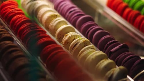 Assorted brightly colored French macarons in display case, right pan into focus
