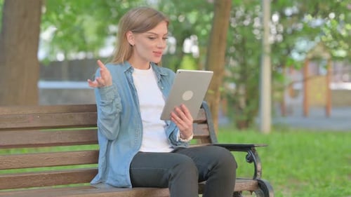 Outdoor Sitting Young Woman Doing Video Chat on Tablet