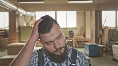 Young Carpenter with a Beard and a Stylish Haircut in the Workshop RAW Video Record