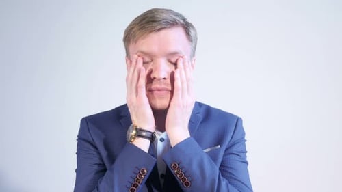Man Massaging Temples in Blue Suit