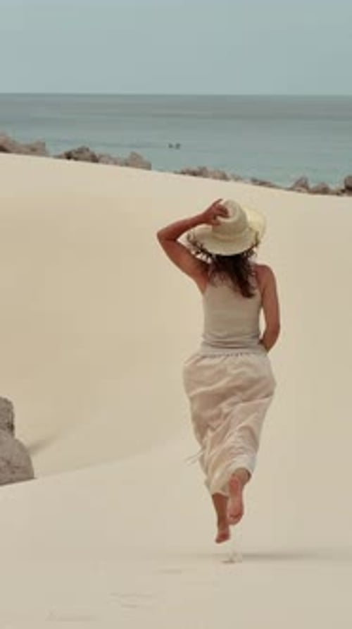 A Woman Strolling Along the Soft Beach Sands with a Gorgeous Ocean View Ahead of Her