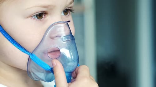 Close Up View of Little Girl are Sitting and Holding a Nebulizer Mask Leaning Against the Face