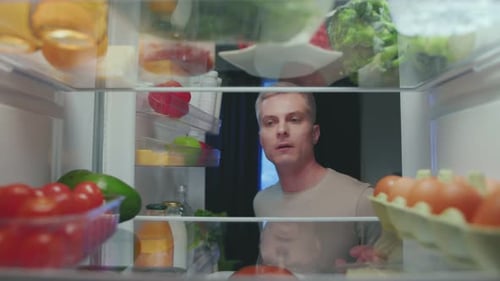 Adult Male Reaching into Refrigerator for Tomatoes