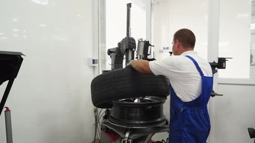 Auto Mechanic Operates Tire Changer in Garage Professional Removes Wheel for Seasonal Replacement