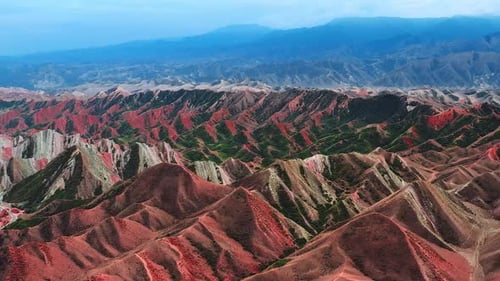 Cinematic Aerial View Of Vibrant Red And Green Mountain Ridges