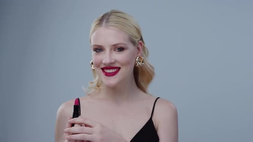 Eine selbstbewusste und stilvolle Frau, die gekonnt Lippenstift aufträgt, während sie in schicker Kleidung gekleidet ist