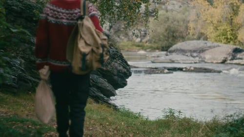 Tourist with Backpack Walking toward River and Enjoying Scenery