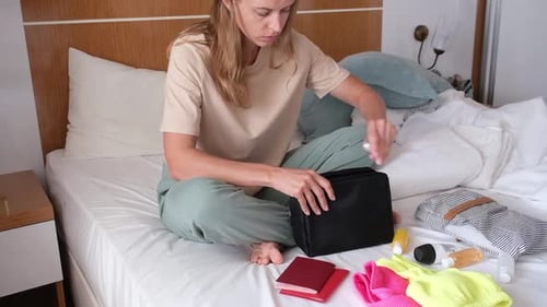 Woman Packing for Vacation on Bed in Hotel Room