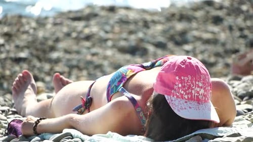 Femme positive méconnaissable en bikini noir prenant un bain de soleil ou bronzant sur la plage en bord de mer pendant l'été