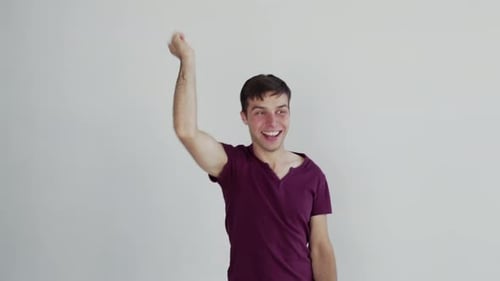 Excited Young Man Cheers with Fist Raised Indoors