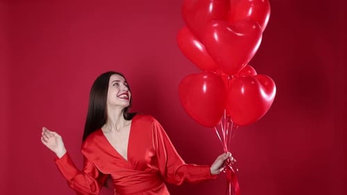 St. Valentine's Day. Beautiful woman with heart shaped balloons on red background