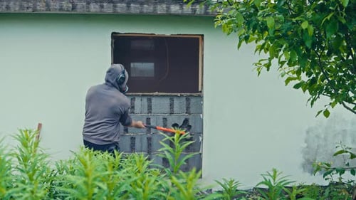 Hombre realizando trabajos de demolición en una pared de ladrillos - Wide Shot