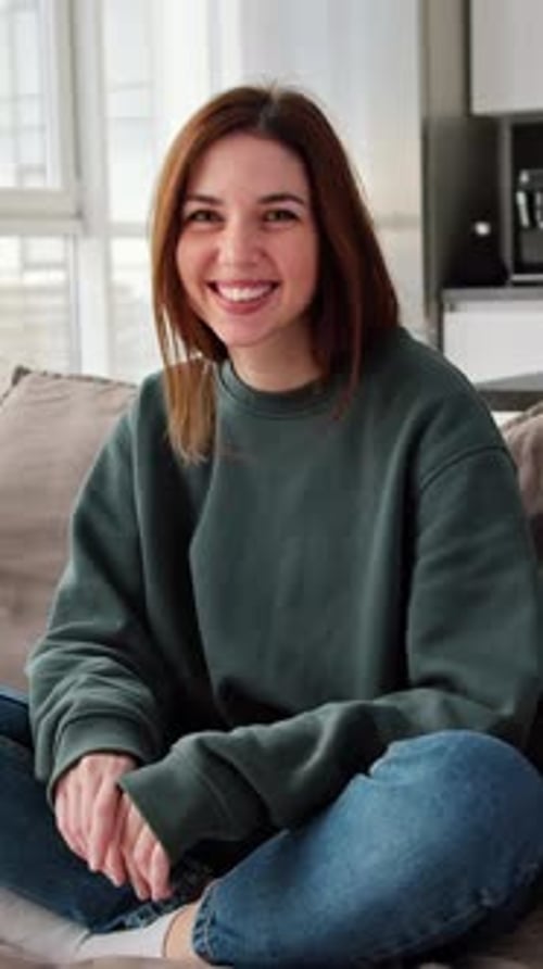 Portrait of a Happy Brunette Girl Sitting on the Sofa at Home
