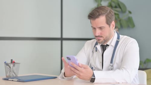 Male Doctor Using Smartphone in Clinic