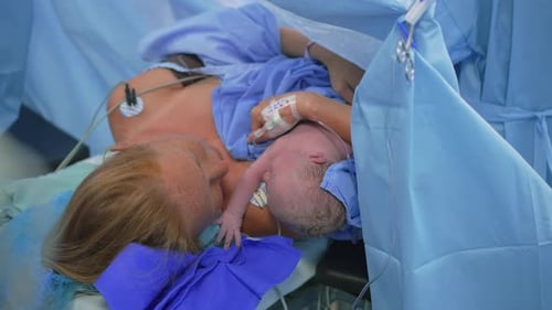 Un bébé à peine né est placé sur la poitrine de la mère pendant que le chirurgien termine la césarienne