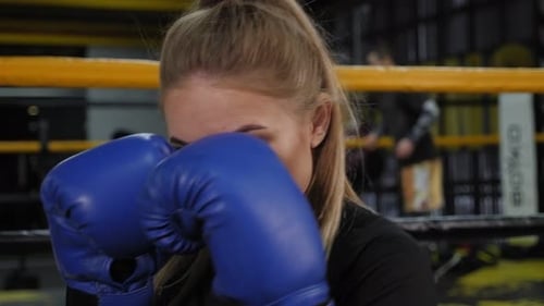 Closeup of a Female Boxer in Blue Boxing Gloves Practicing a Punch in the Gym