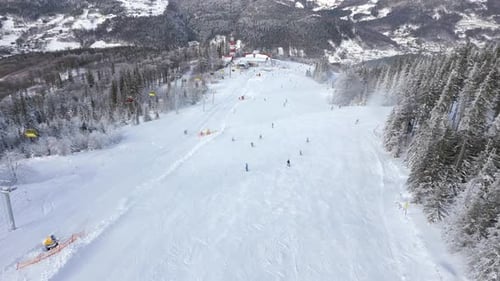 Aerial of Snowy Ski Slope with People Skiing and Chairlifts in Mountain Resort