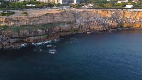 Golden Hour Aerial View of Sunlight Hitting Dramatic Coastal Cliffs