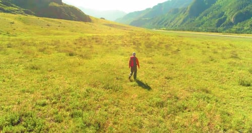 Flight Over Backpack Hiking Tourist Walking Across Green Mountain Field Huge Rural Valley at Summer