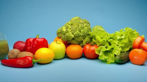 Orange Dumbbells Surrounded with Healthy Fruits and Vegetables Studio Shot on Blue Background