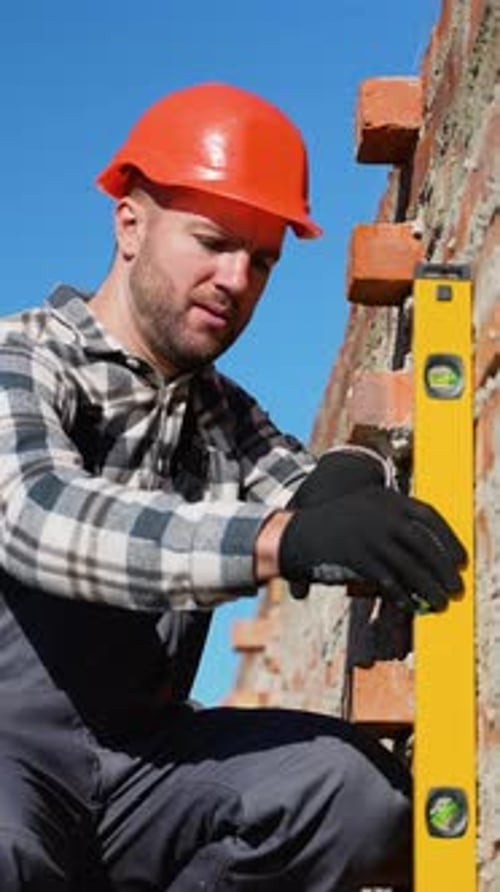 Builder Checking Wall Alignment with Level Tool