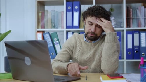Frustrated man using laptop at desk