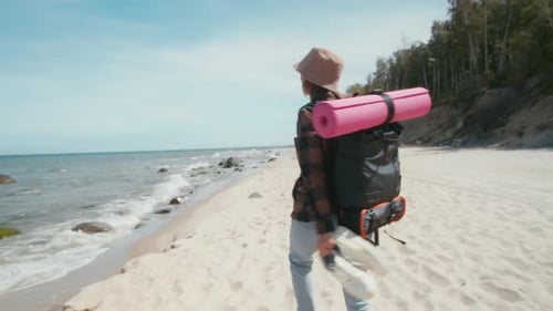 Woman traveler walks along a wild beach