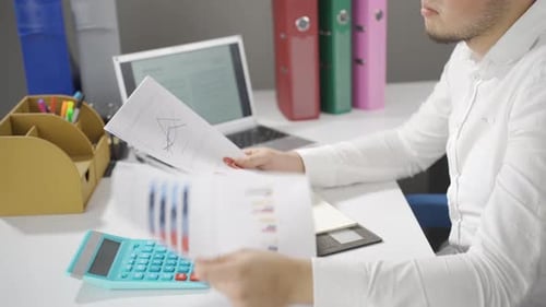 Young Adult Analyzes Charts and Graphs at Desk