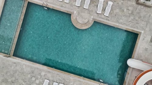 Aerial Video of Swimming Pool with Aqua Slide and Lounge Chairs in Courtyard Area