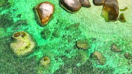 Stunning sandy beach with rock and clean sea water by aerial view. 4K.