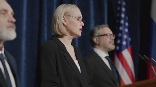 Woman Speaks at Press Conference with Flags