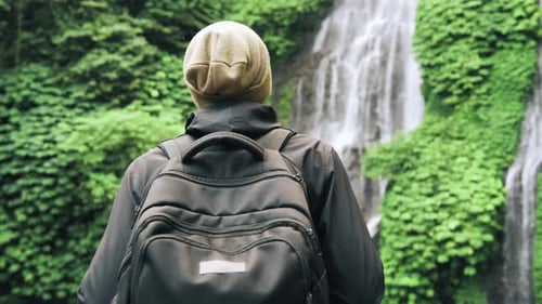 Traveling Man Walking in Green Nature of Forest Landscape to Mountain Waterfall