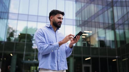 Man Using Mobile Phone Near Modern Office Building