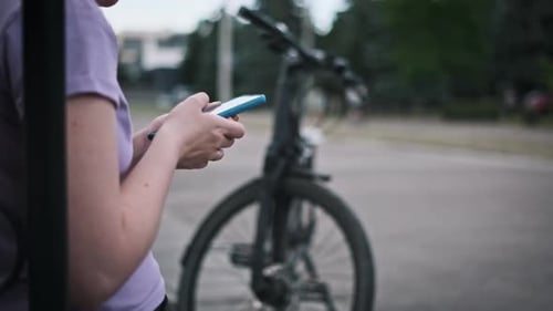 Woman Using Smartphone With Bicycle in Urban Setting