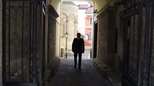 Man Walks Through Stone Archway
