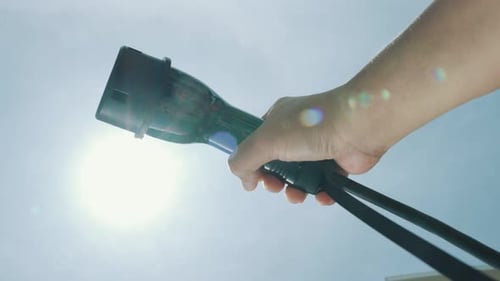 Nahaufnahme der Hand, die einen EV-Stecker für Elektrofahrzeuge als fortschrittliche Idee fasst