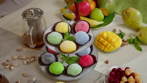 Ein Teller mit Mochi-Kuchen steht auf dem Tisch und auch ein Wasserkocher mit Tee und Obst